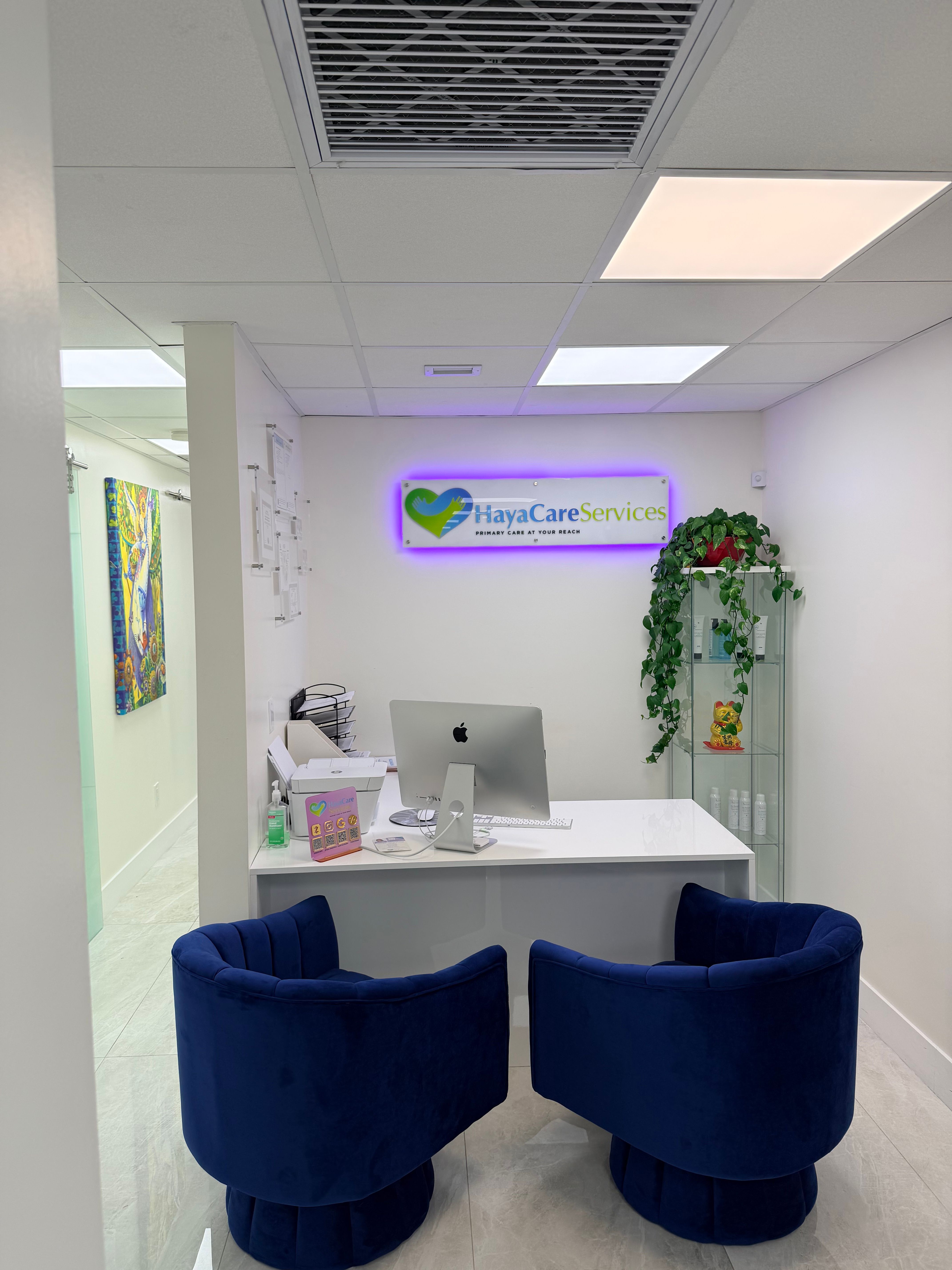 The HayaCare reception desk with its lit sign and two blue armchairs